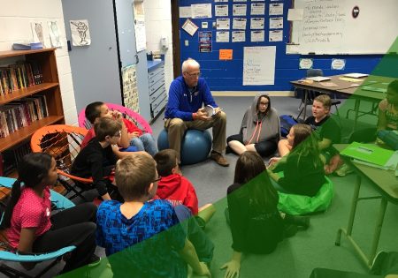 Superintendent reading to a group of children sitting in a circle in a classroom