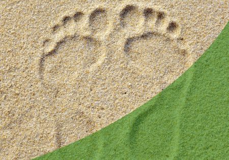 Foot prints in sand with a green swoosh over the bottom right
