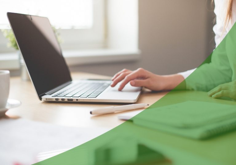 Person on a laptop on a desk with a green swoosh on the lower right
