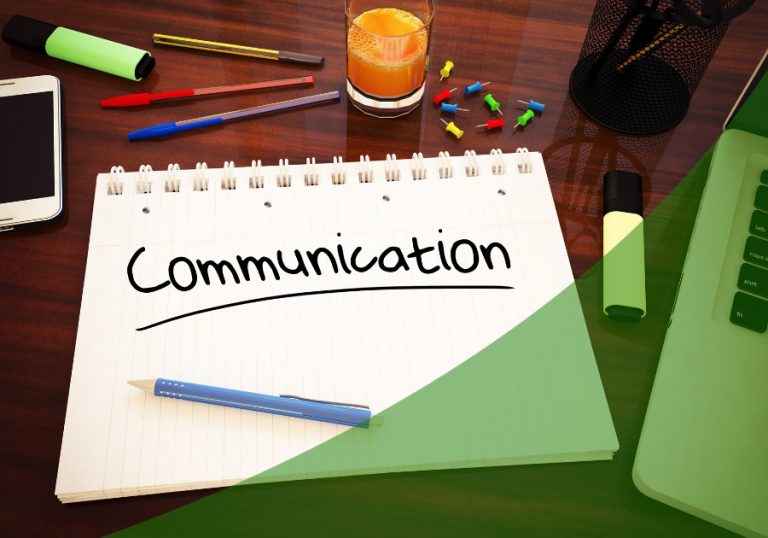 Image of a desk with a notepad and pen that reads Communication with a green swoosh across the lower right of the image