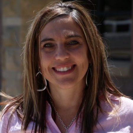 headshot of a business woman in a pink shirt standing outside
