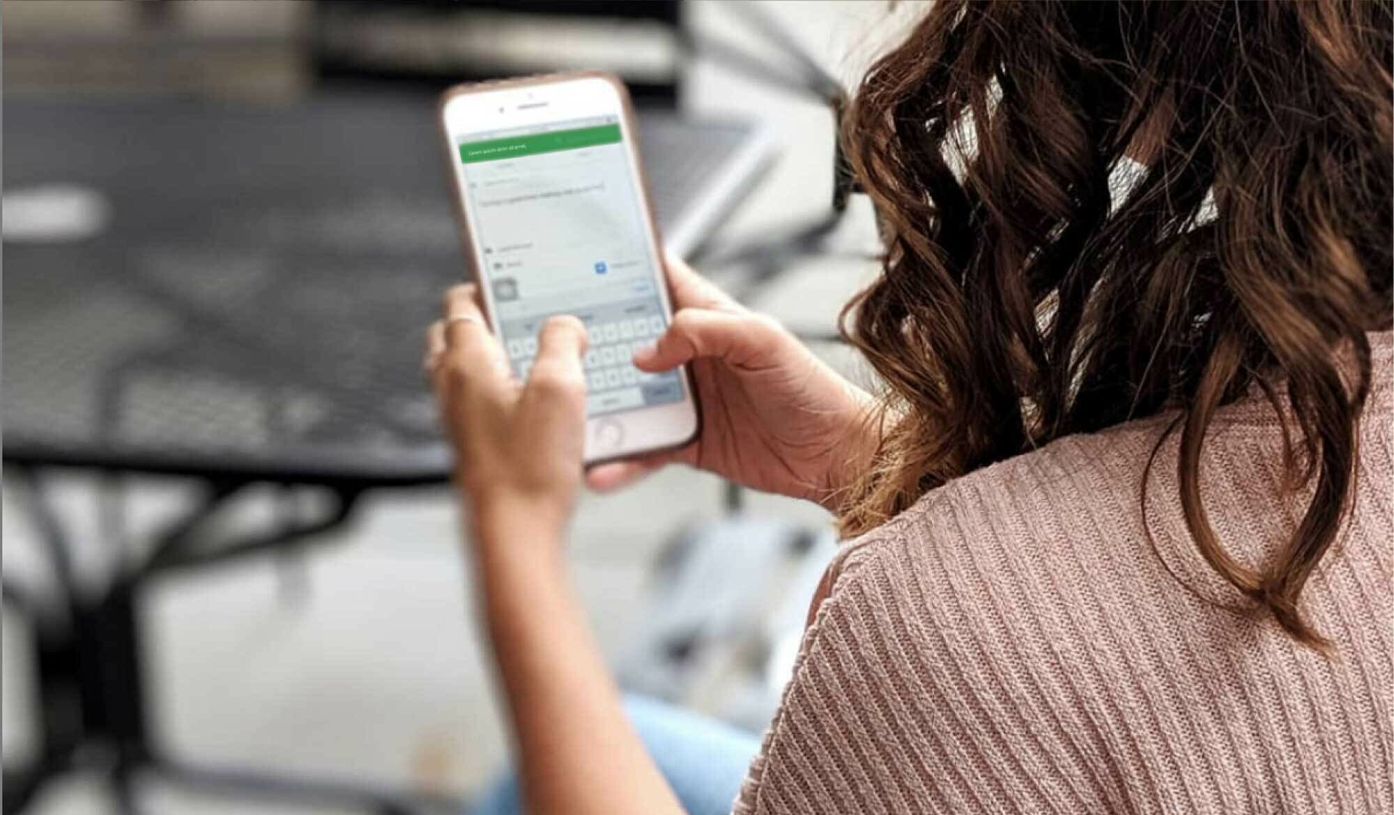 Women sitting outside holding a phone in her hands