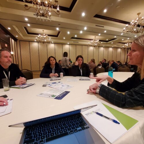 Class Intercom President, Jill, sitting a table with other education professionals at a conference.