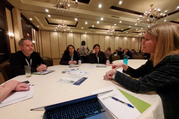 Class Intercom President, Jill, sitting a table with other education professionals at a conference.