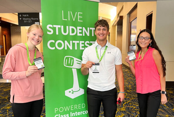 Three students standing in front of a class intercom banner
