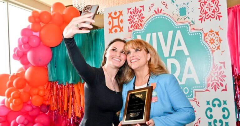 Two people taking a selfie in front of a vibrant background