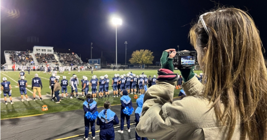 A girl taking photos at a high school football game