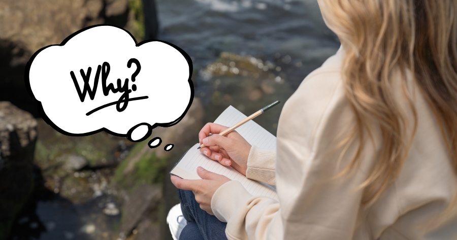 A person with blonde hair wearing a beige top and dark jeans sits outdoors by what appears to be water and rocks, writing in a notebook with a pencil. A thought bubble with the word "Why?" in a handwritten style floats above their head.
