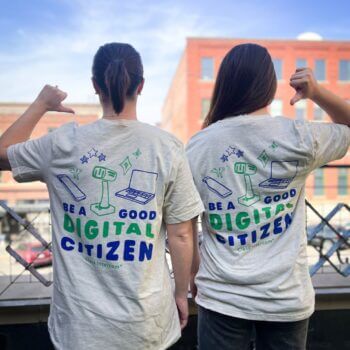Two people wearing Class Intercom “Be a Good Digital Citizen” shirts, promoting digital responsibility in schools.