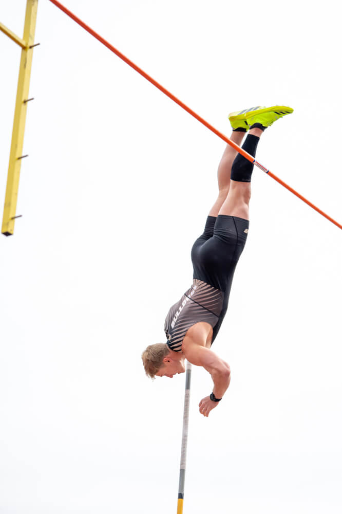 Kalen Knott, a four-time conference champion pole vaulter for Bryant University, clears the bar mid-vault.